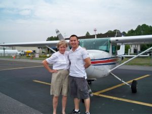 A man and woman standing in front of an airplane.