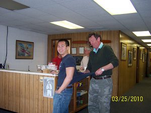Two men standing in a room with a bar.