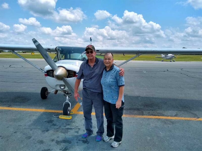 A man and woman standing in front of an airplane.