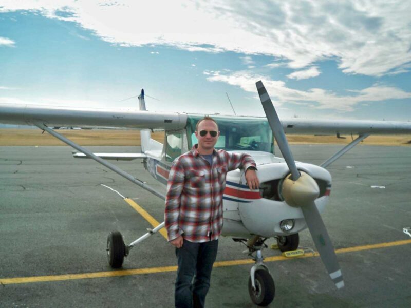 A man standing next to an airplane on the tarmac.