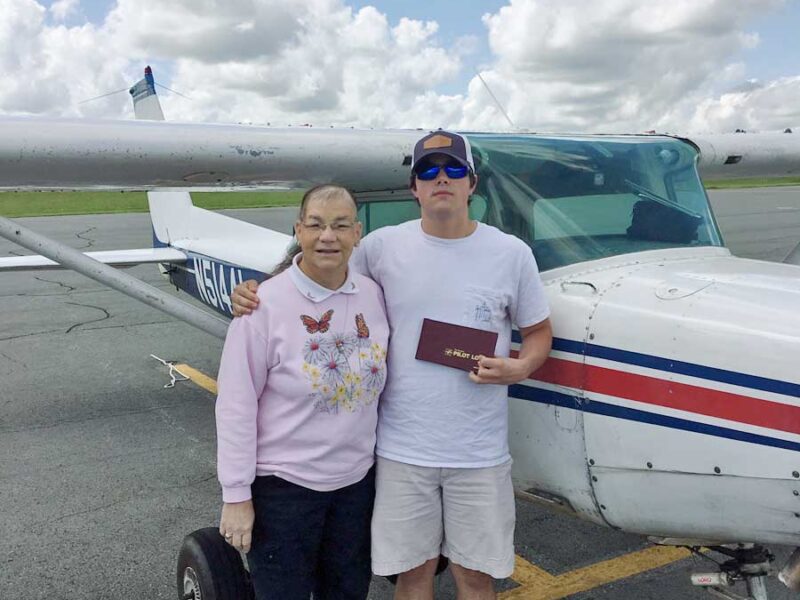 A man and woman standing in front of an airplane.