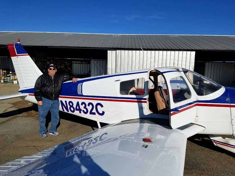 A man standing next to an airplane in front of a building.